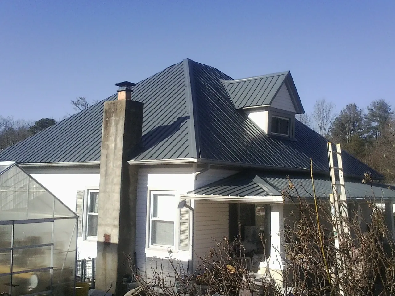 Dark blue standing seam metal roof on a white farmhouse with dormer — Slate & Tile Roof Repair by Roofing Brothers in Descanso