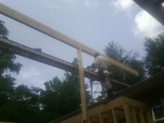 Carpenter setting a ridge beam over a new addition frame — Ice Dam Removal by Roofing Brothers in Descanso
