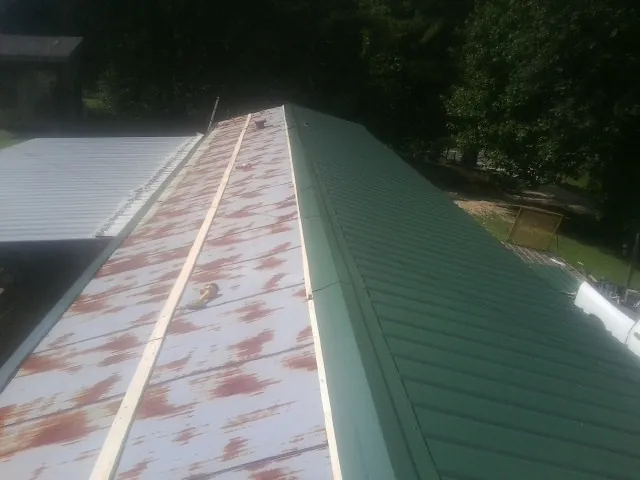 Old rusted panels beside newly installed green metal roofing — Wind Damage Roof Repair by Roofing Brothers in Descanso