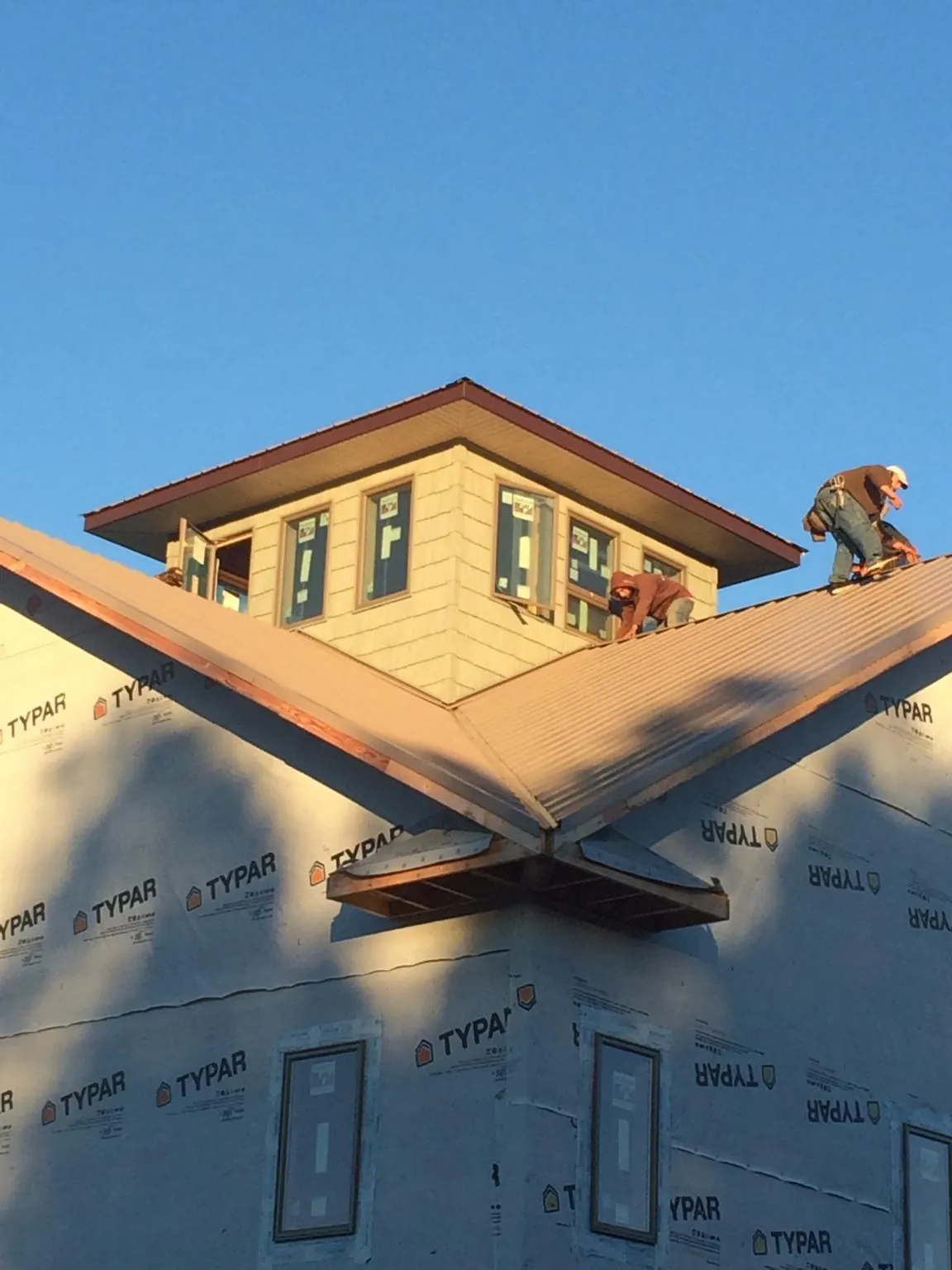 Roofers working around a rooftop cupola on a new metal roof at sunset — Roof Waterproofing in Descanso by Roofing Brothers